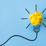 A crumpled yellow piece of paper forms the bulb of a cartoon lightbulb