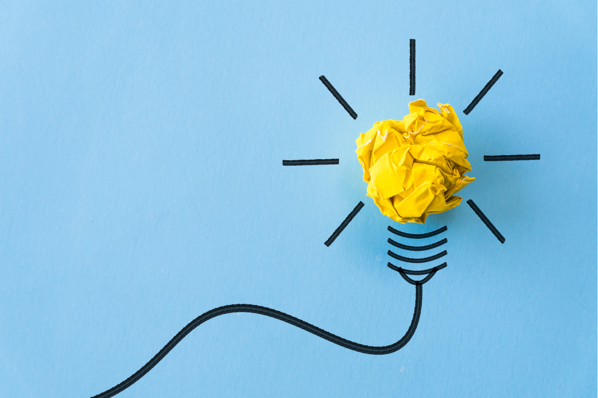 A crumpled yellow piece of paper forms the bulb of a cartoon lightbulb