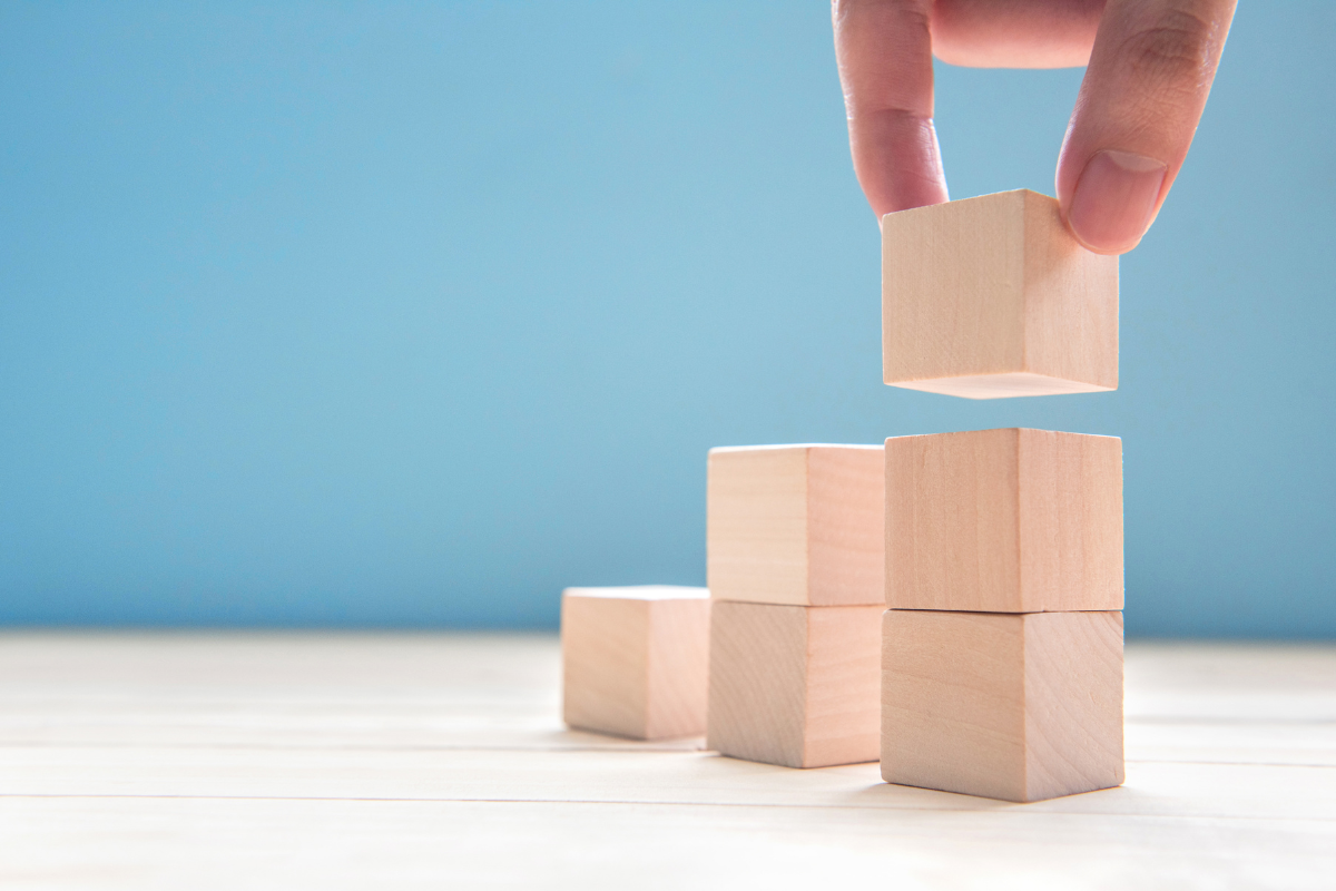 A person adds a wooden block to a stack, forming an upward graph