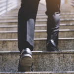 A person in business attire walking up concrete stairs