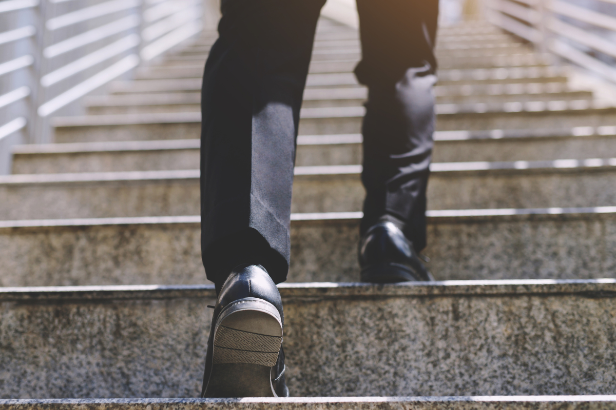 A person in business attire walking up concrete stairs