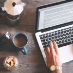 A person performs professional editing on a laptop next to a mug of coffee