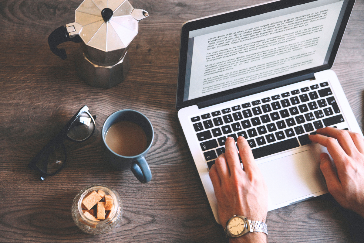 A person performs professional editing on a laptop next to a mug of coffee