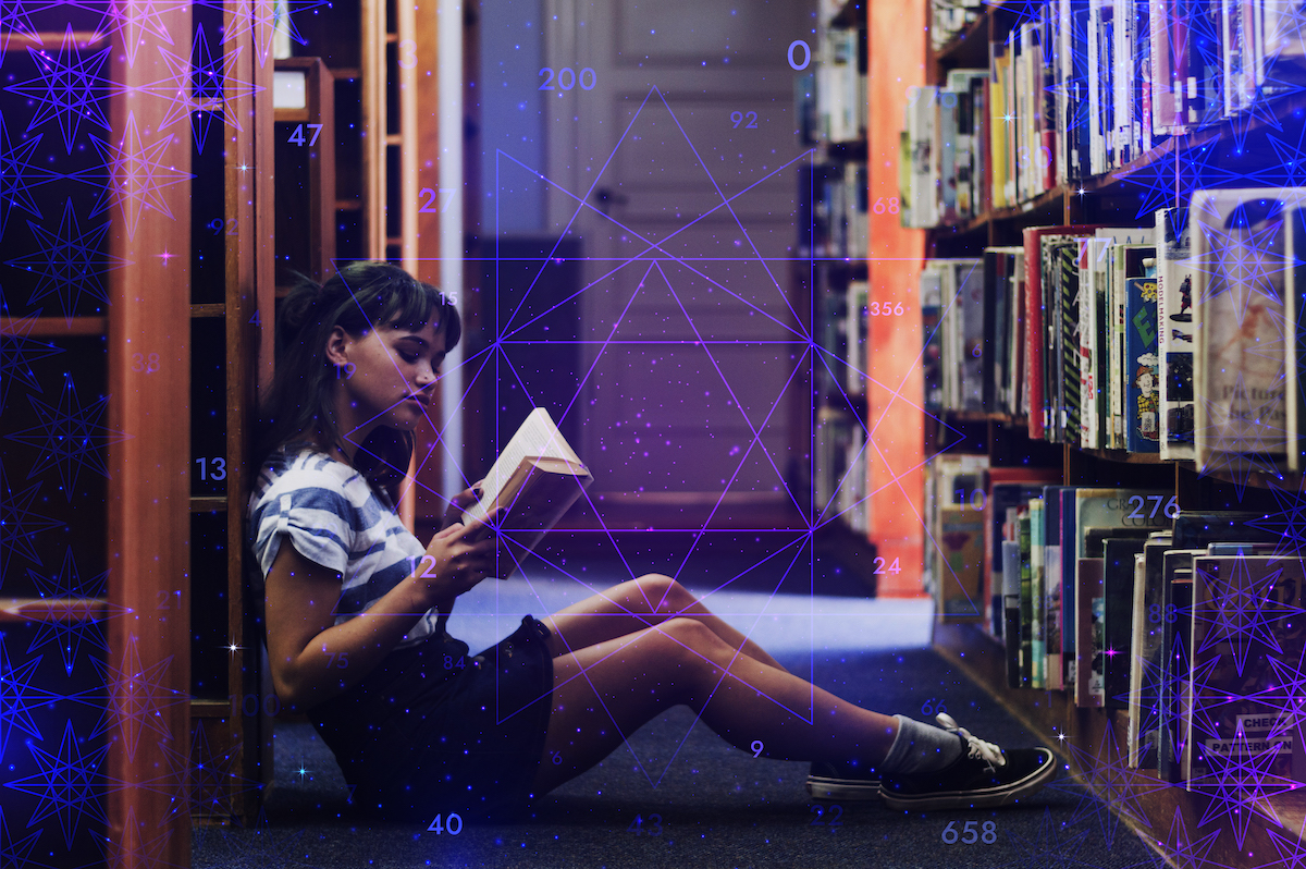A person reads a book in an aisle of book shelves
