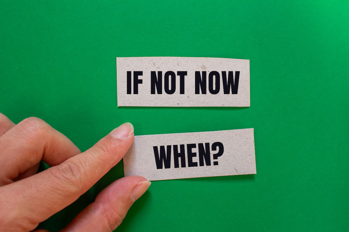 A person adjusts slips of paper that say "if not now when?"