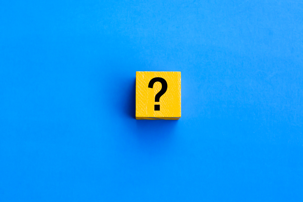 A wooden block with a question mark on it on a blue background