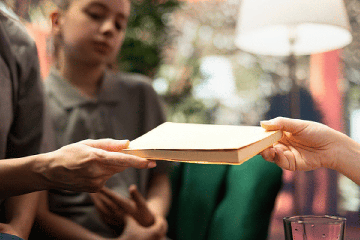 A person hands a book to someone else