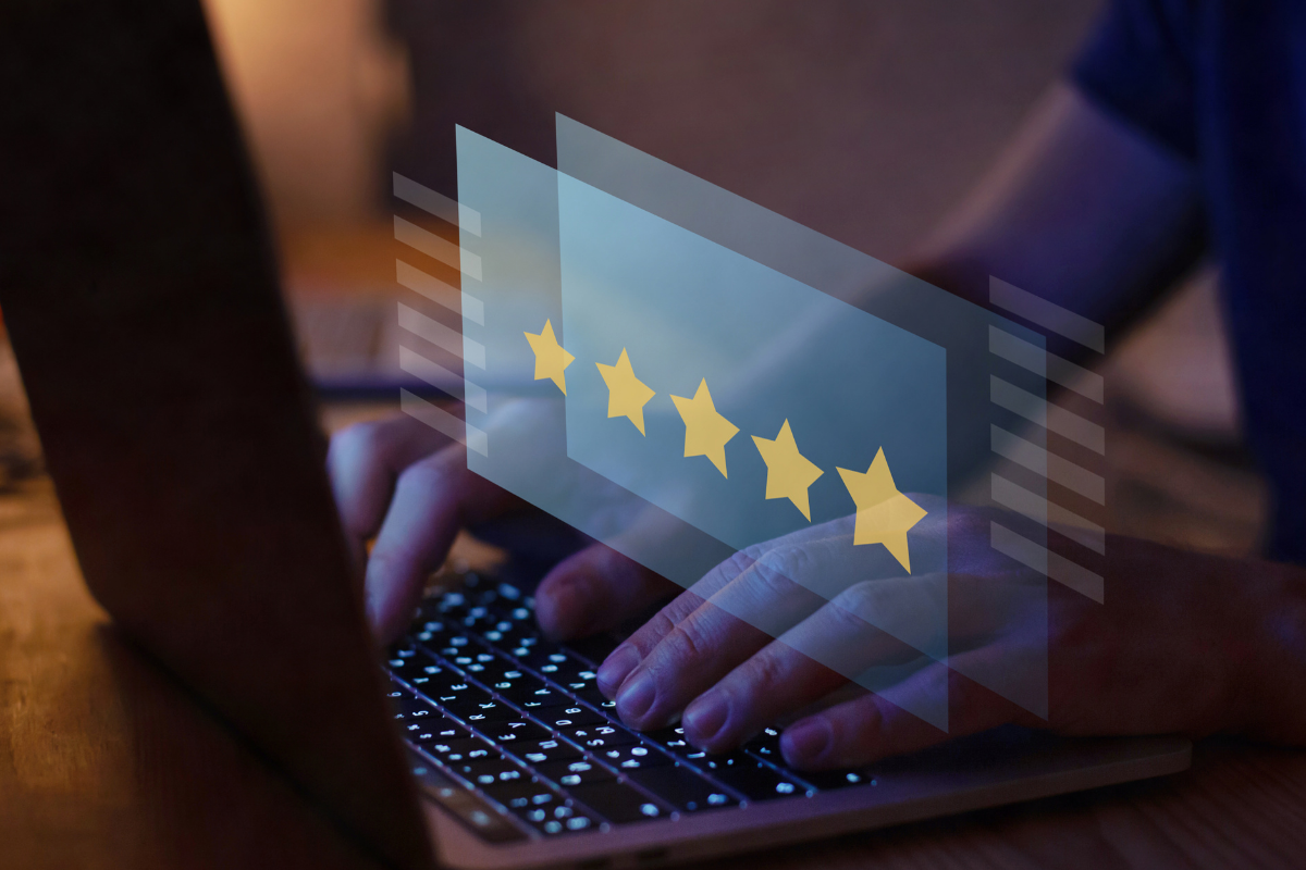 A Person types a five star review on a laptop