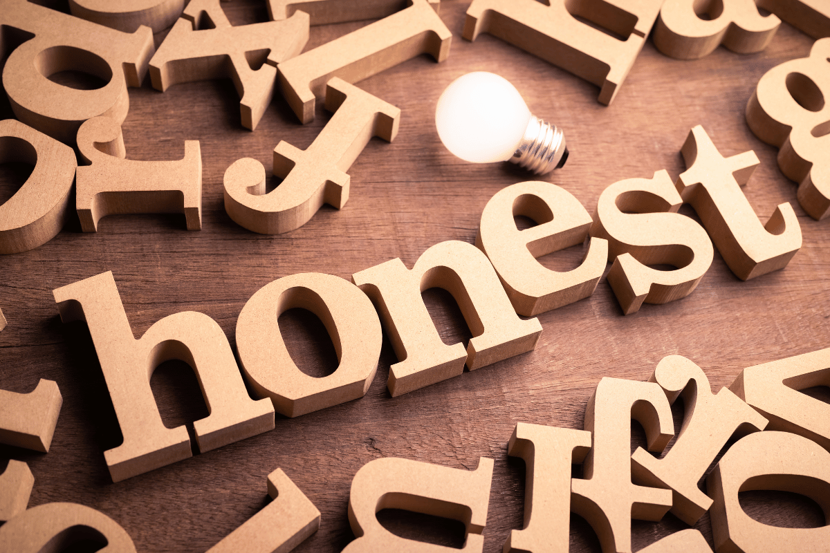 Wooden letters scattered around the word "honest" with a lightbulb nearby