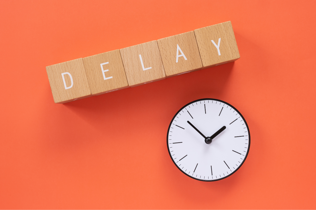 The word delay written on wooden blocks next to a clock
