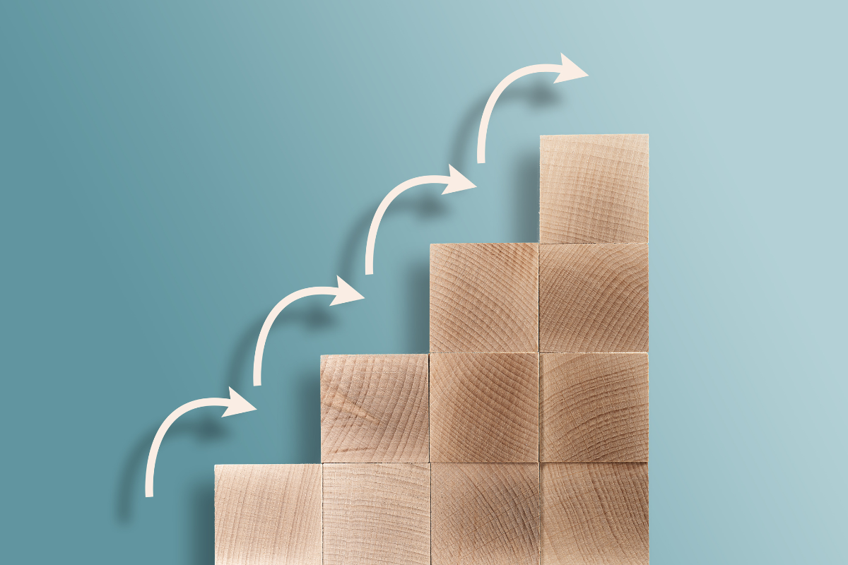 An upward leaning stack of blocks with arrows indicating a step-by-step process