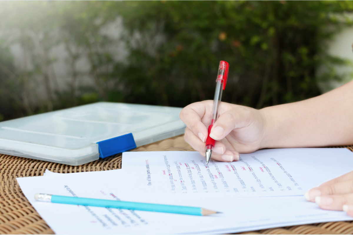 An editor marks up a document with a red pen