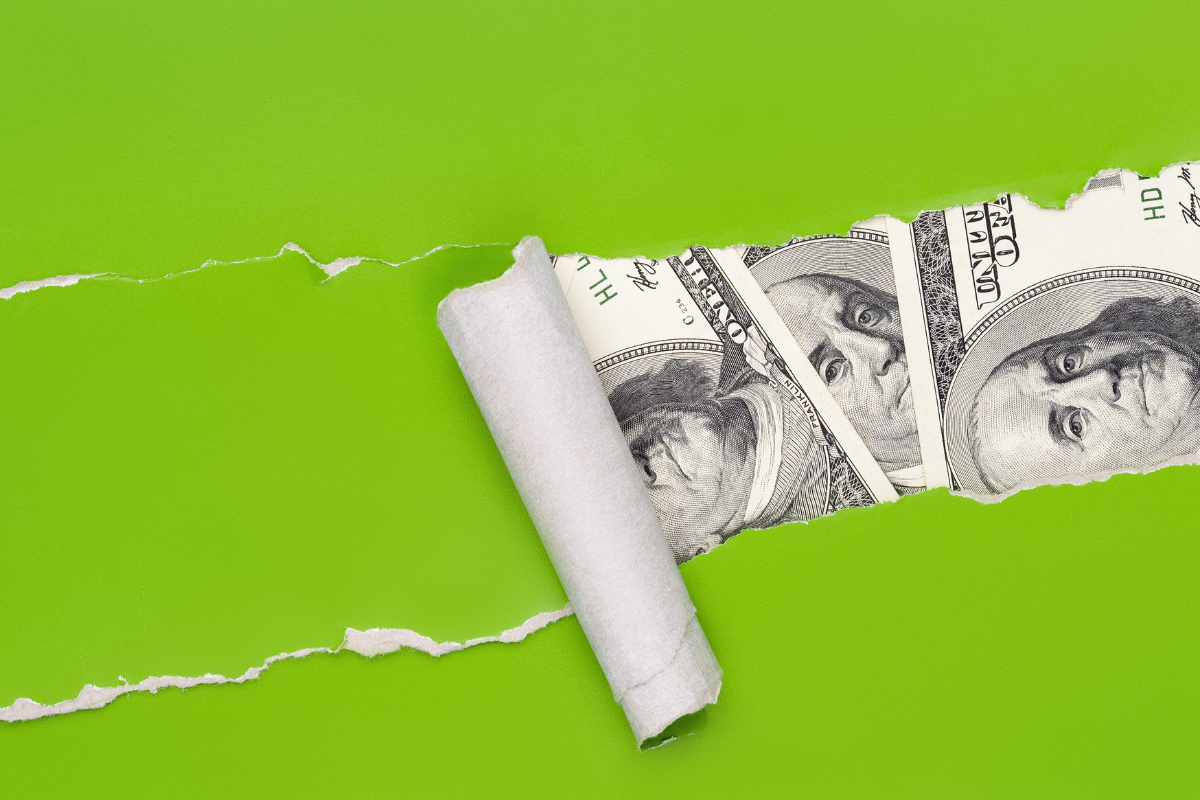 Hundred dollar bills visible behind a green paper foreground