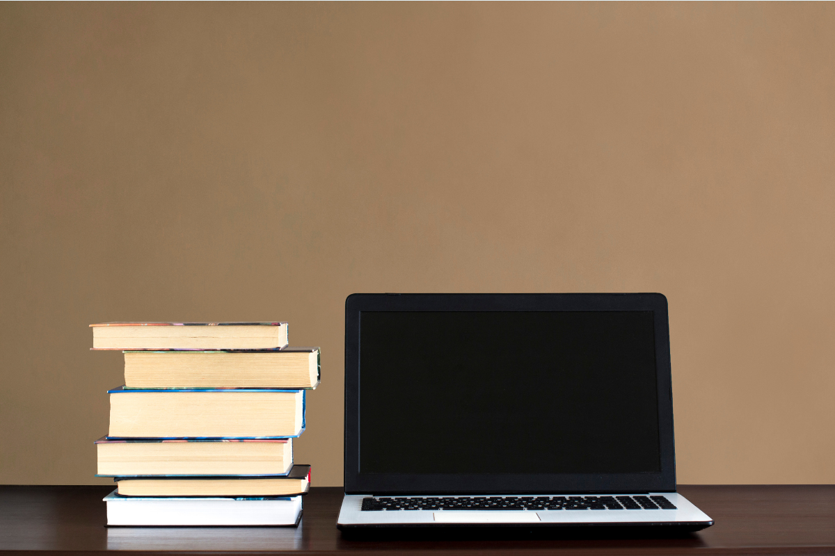A stack of books next to an open laptop