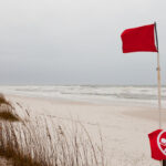 Red flags on a Gulf Coast Beach signal swimming in ocean prohibited due to dangerous surf, undercurrent and storm conditions