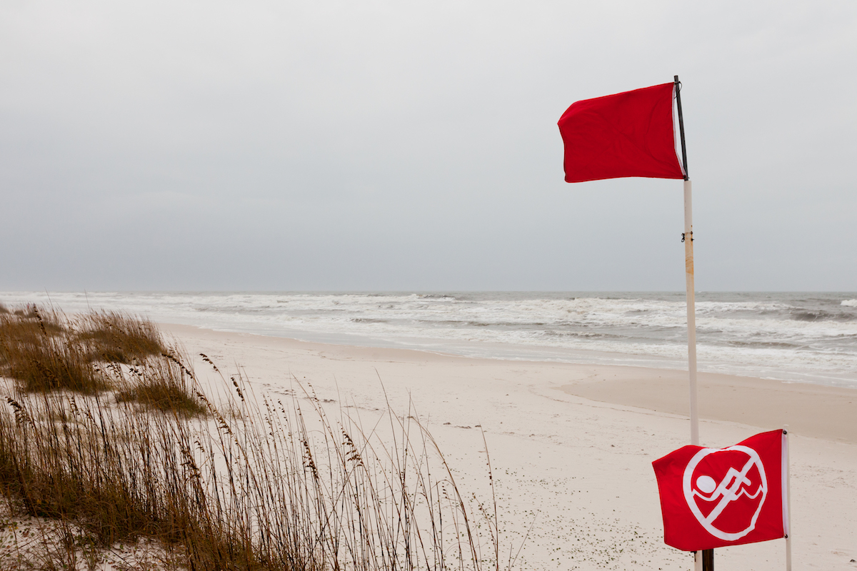 Red flags on a Gulf Coast Beach signal swimming in ocean prohibited due to dangerous surf, undercurrent and storm conditions
