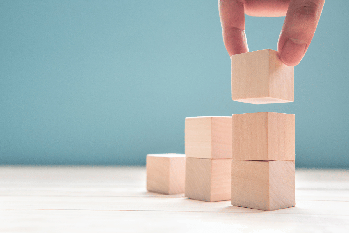 A person adds a wooden block to a tower