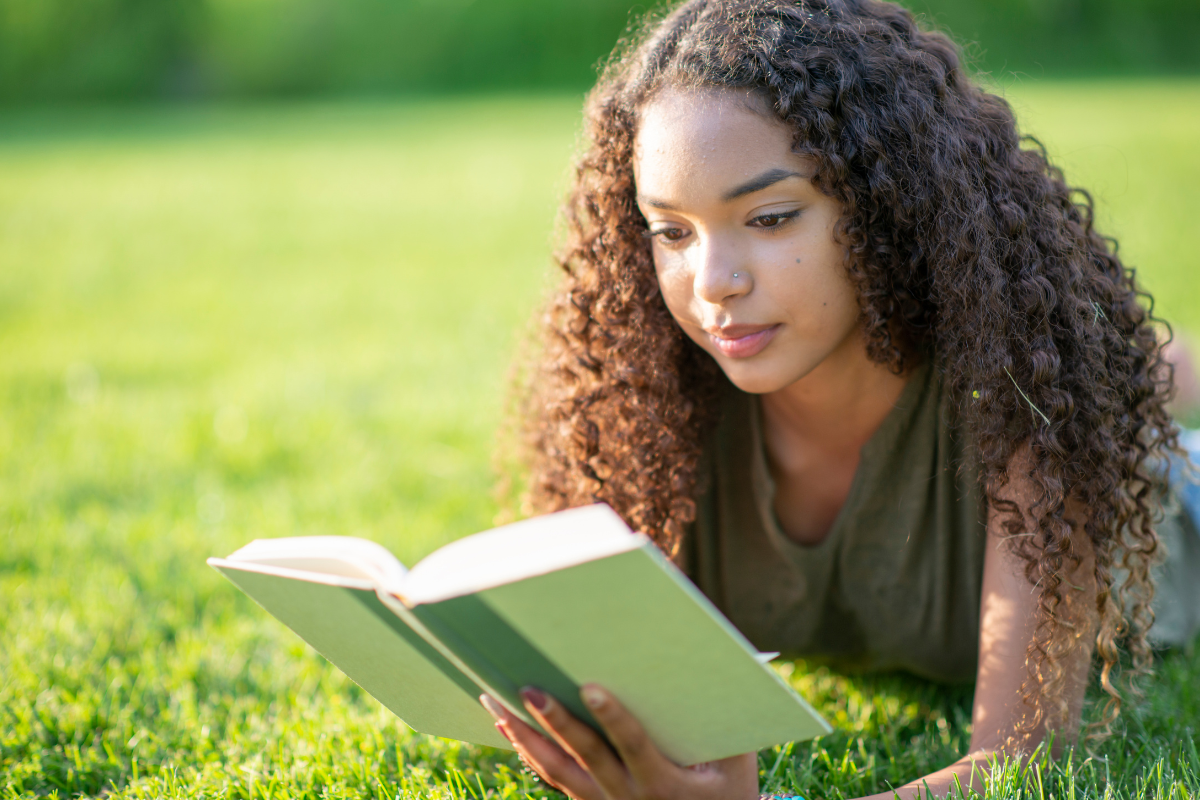 A person reading a book in the grass